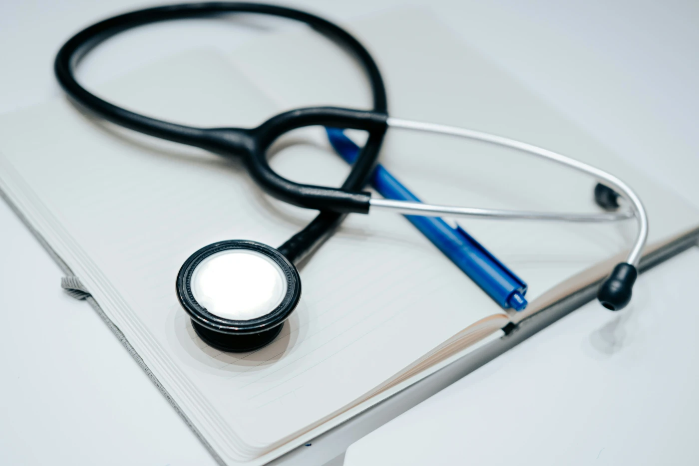 A black stethoscope and a pen resting on an open notebook, the kind of clinical setup used to record a hantavirus exposure history.