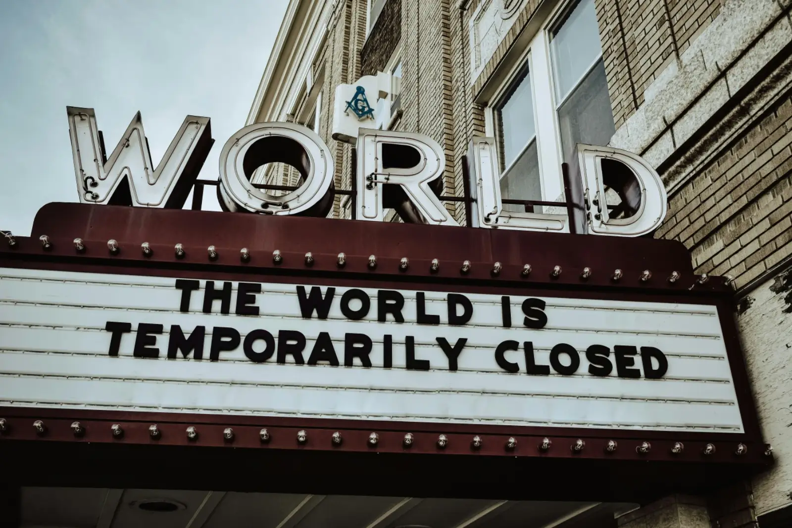 A theatre marquee with the message "The world is temporarily closed", an emblem of how outbreak response reshapes public spaces.